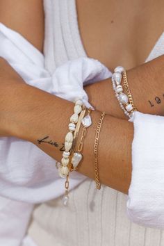 Flanked with natural white puka shells and pikake flowers, this unique shell bracelet evokes visions of Hawaii's white sands and soothing shores. Stack this gold bracelet with other beaded beauties and you'll be ready for your tropical escape.✦ DETAILS ✦✧ Name: Me'e (MAY aye) - Heroine.✧ Adjustable from 6.5"-8".✧ 6-7mm White Puka Shells.✧ Carved Resin Pikake Flowers.✧ 14kt Gold Filled with lobster clasp.✧ All Ke Aloha Jewelry pieces come packaged thoughtfully, beautifully, and ready for gift giv Gold Pearl Bracelet With Pearl Charm For Beach, Gold Pearl Charm Bracelet For Beach, Gold Bracelet With Pearl Charm For Beach, White Pearl Bracelet With Charm For Beach, Pearl Beaded Bracelets For Beach, Bohemian Pearl Bracelets For The Beach, Bohemian Pearl Bracelets For Beach, White Pearl Jewelry For Vacation, White Bracelets With Pearl Charm For Beach