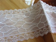 two pieces of white lace sitting on top of a wooden table