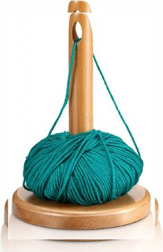 a green ball of yarn sitting on top of a wooden stand next to a crochet hook