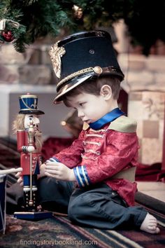 a little boy dressed up as a nutcracker playing with a toy soldier on the floor