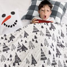 a young boy laying in bed with a snowman pillow and blanket on top of him