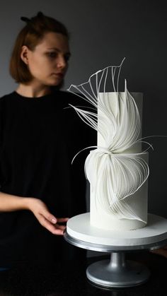 a woman standing next to a cake with white icing on it's side