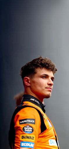 a man in an orange racing suit looking off to the side with his head tilted