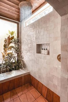 a bathroom with tiled walls and flooring next to a large window that looks out onto the outdoors