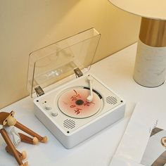 a record player sitting on top of a white table next to a lamp and pictures