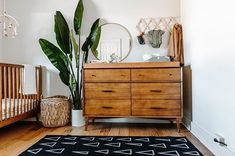 a baby crib and dresser in a room with wood floors, white walls and wooden furniture