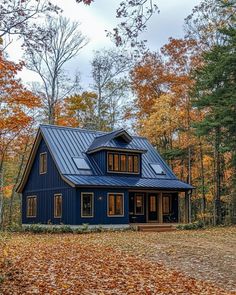 a blue house surrounded by trees in the fall