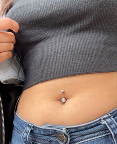 a woman's stomach with a piercing on the side and a zippered jacket behind her