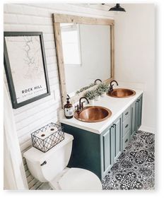 a white toilet sitting next to a bathroom sink under a wooden mirror mounted above it