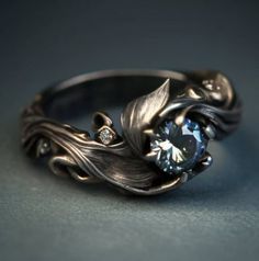 a silver ring with a blue stone in the center and vines on it's side