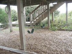 there is a swing set in the middle of an empty yard with stairs leading up to it