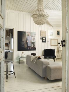 a living room filled with furniture and a chandelier hanging from the ceiling in front of a painting