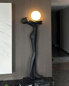 a lamp that is sitting on top of a black stand in front of a wall