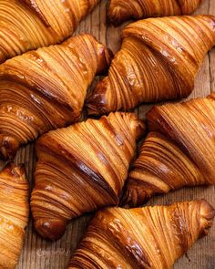 several croissants are lined up on a wooden surface with chocolate sauce drizzled on them