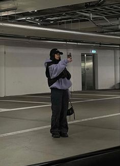 a person taking a selfie with a cell phone in an empty parking garage area