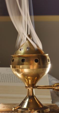 a golden incense burner sitting on top of a table next to an open book