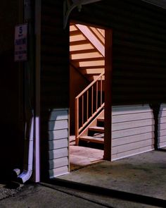 an open door leading into a dark room with stairs on either side and light coming in from the window