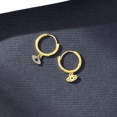 Add a touch of interest to your ensemble with these Evil Eye Earrings. Carefully crafted from 925 sterling silver with 14K gold plating, these earrings offer exquisite detail and durability, and Evil Eye protection!Details:- Huggie Style Hoops- 14K Gold Plated 925 Sterling SilverDimensions:- Length Approx. 0.6" from Top of Hoop to Bottom of Charm- Width of Hoop Approx. 0.5" The Moon Tarot Card, The Moon Tarot, Evil Eye Protection, Evil Eye Earrings, Eye Earrings, Eye Protection, Body Oil, Gold Plating, Evil Eye