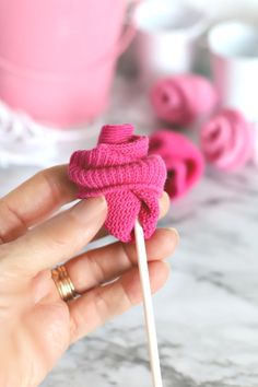 a hand holding a pink lollipop on a stick