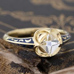 a diamond ring sitting on top of a piece of wood next to an old book