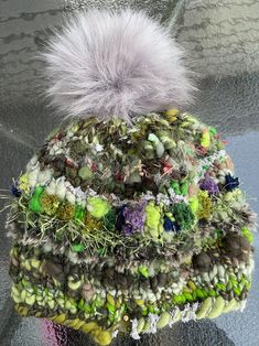 a multicolored knitted hat with a white pom - pom on top