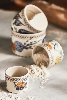 three cups sitting next to each other on top of a white table covered in sand