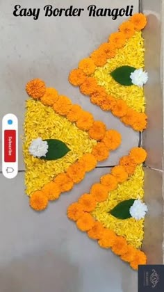 two pieces of yellow and orange flowers are on the floor next to a wall with an easy border rangoli