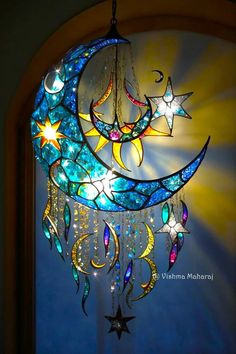 a stained glass chandelier with stars and moon designs hanging from it's side