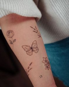 a woman's arm with a butterfly and flowers tattoo on the left side of her arm