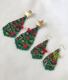 three beaded christmas tree earrings on a white surface