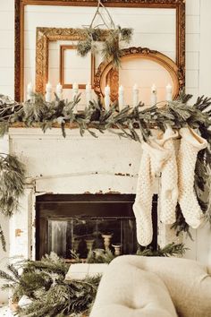 a living room decorated for christmas with greenery and stockings on the fireplace mantel