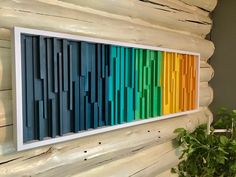 a colorful wall hanging on the side of a wooden building next to a potted plant