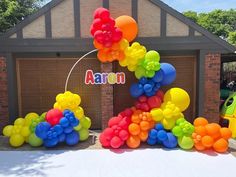 an arch made out of balloons in front of a building with the word aaron on it