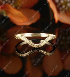 an elegant wedding ring is shown in front of some leaves and flowers, with the reflection of