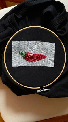 a black bag with a red chili pepper embroidered on it and a white back ground