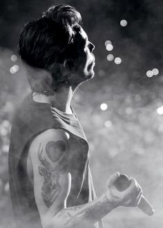 black and white photograph of a man with tattoos on his arm holding a baseball bat