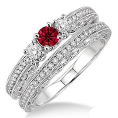 a white gold ring with a red stone in the center and two rows of diamonds around it