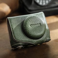 a green leather camera case sitting on top of a table