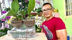 a man standing in front of a potted plant on top of a wooden table