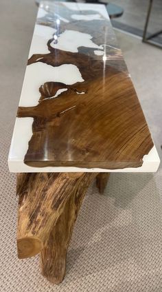 a table made out of wood and glass with white paint on the top, sitting on carpeted flooring