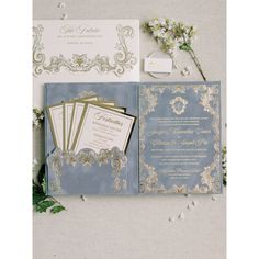 wedding stationery with blue and gold colors on the inside, along with white flowers