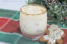 a drink and two cookies on a table with christmas decorations in the backgroud