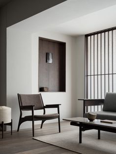 a living room with two chairs and a coffee table in front of a wall mounted shelf