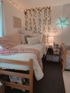 a bedroom with twin beds and string lights hanging from the wall above them is decorated with greenery