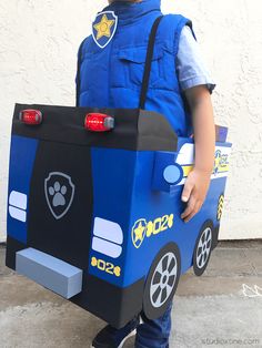 a young boy dressed up as a police officer with a cardboard box on his back