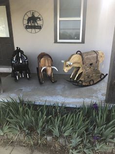 three wooden animals are sitting on the front porch and one is riding a sleigh