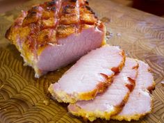 sliced ham sitting on top of a wooden cutting board next to another piece of meat