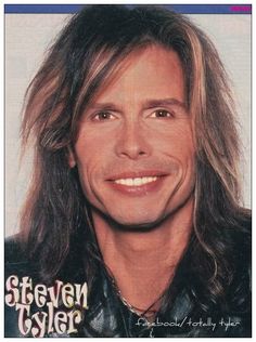 a man with long hair wearing a leather jacket and smiling at the camera while standing in front of a magazine cover