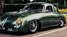 a green sports car parked in a parking lot next to a tree and shrubbery