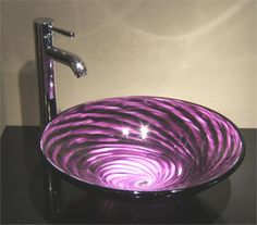 a purple glass bowl sink sitting on top of a black counter